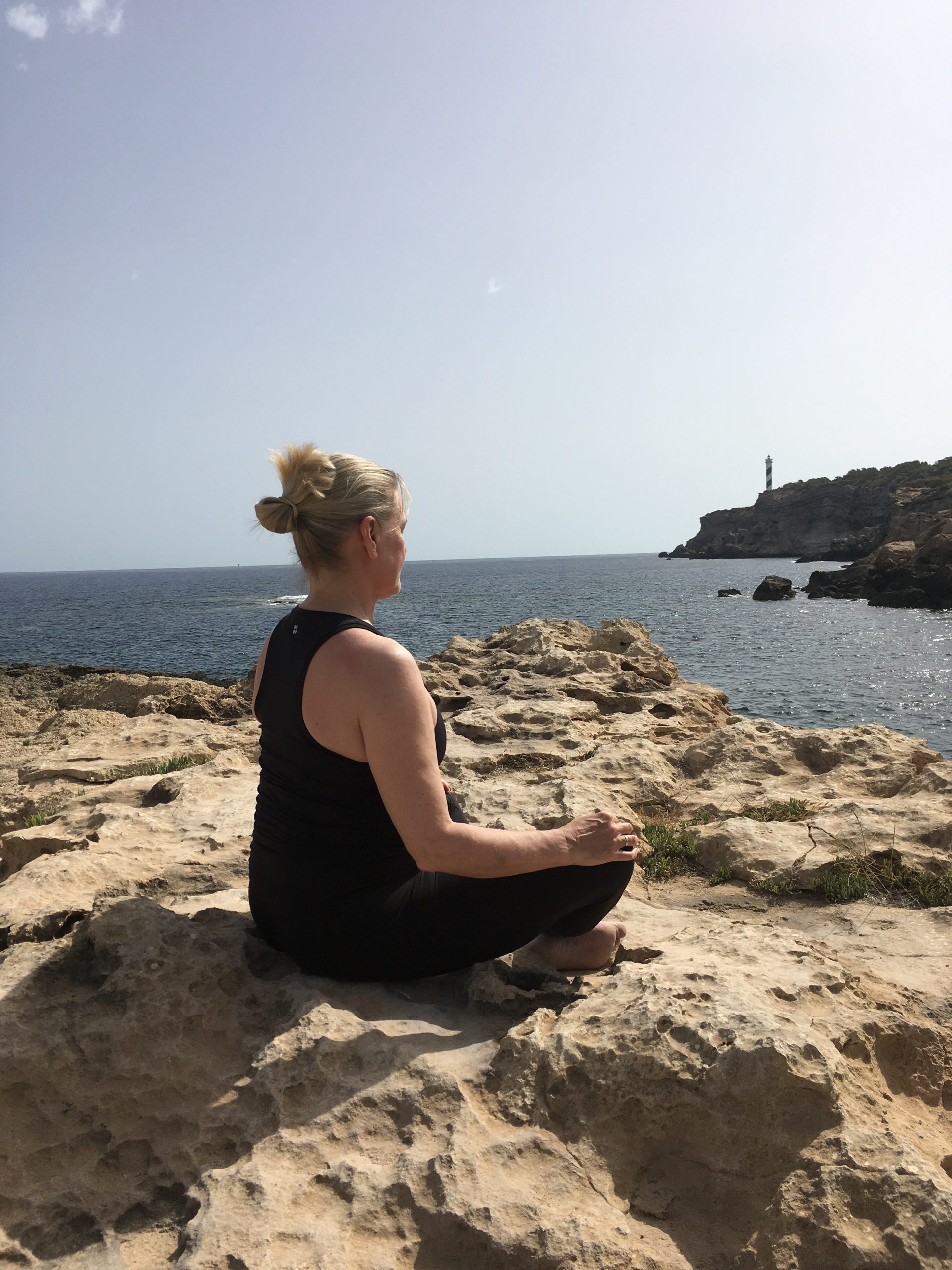 Kirsty sitting on a rock meditating